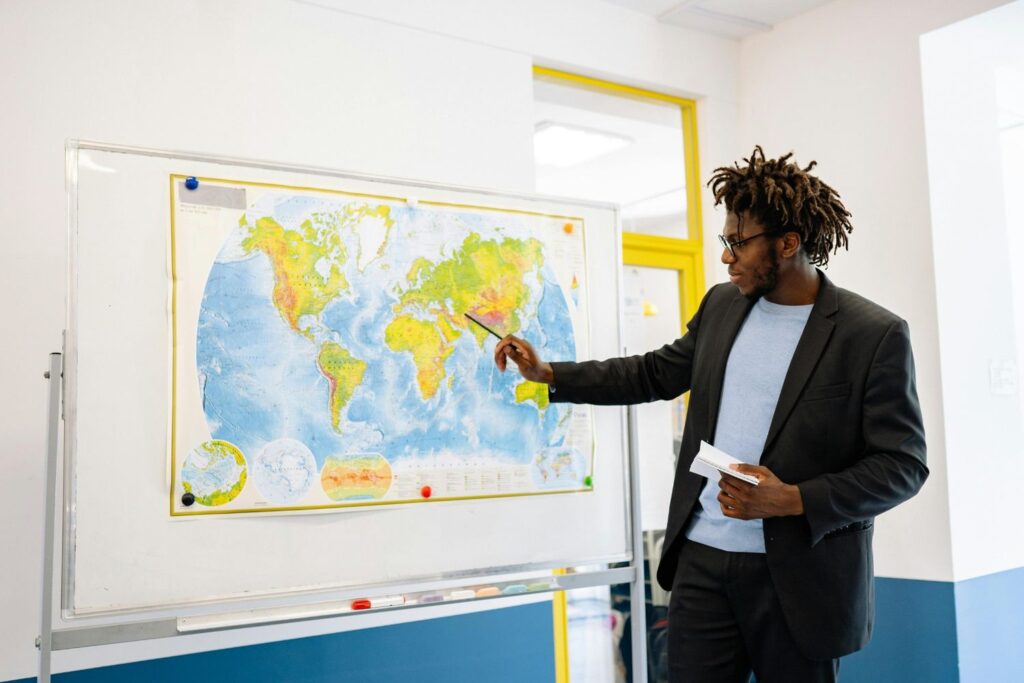 Man standing at whiteboard with image of a map, teaching to students