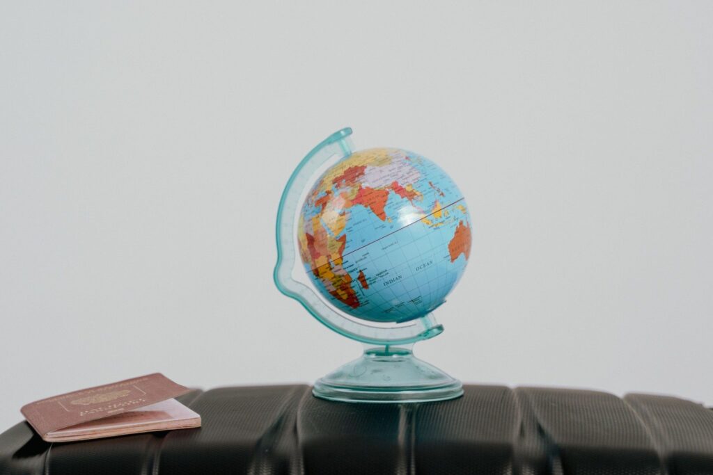 Passport and globe beside luggage while preparing to teach abroad